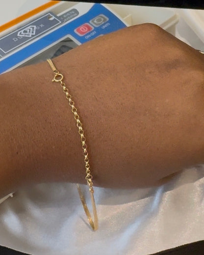 Gold bracelet on a wrist with a white background