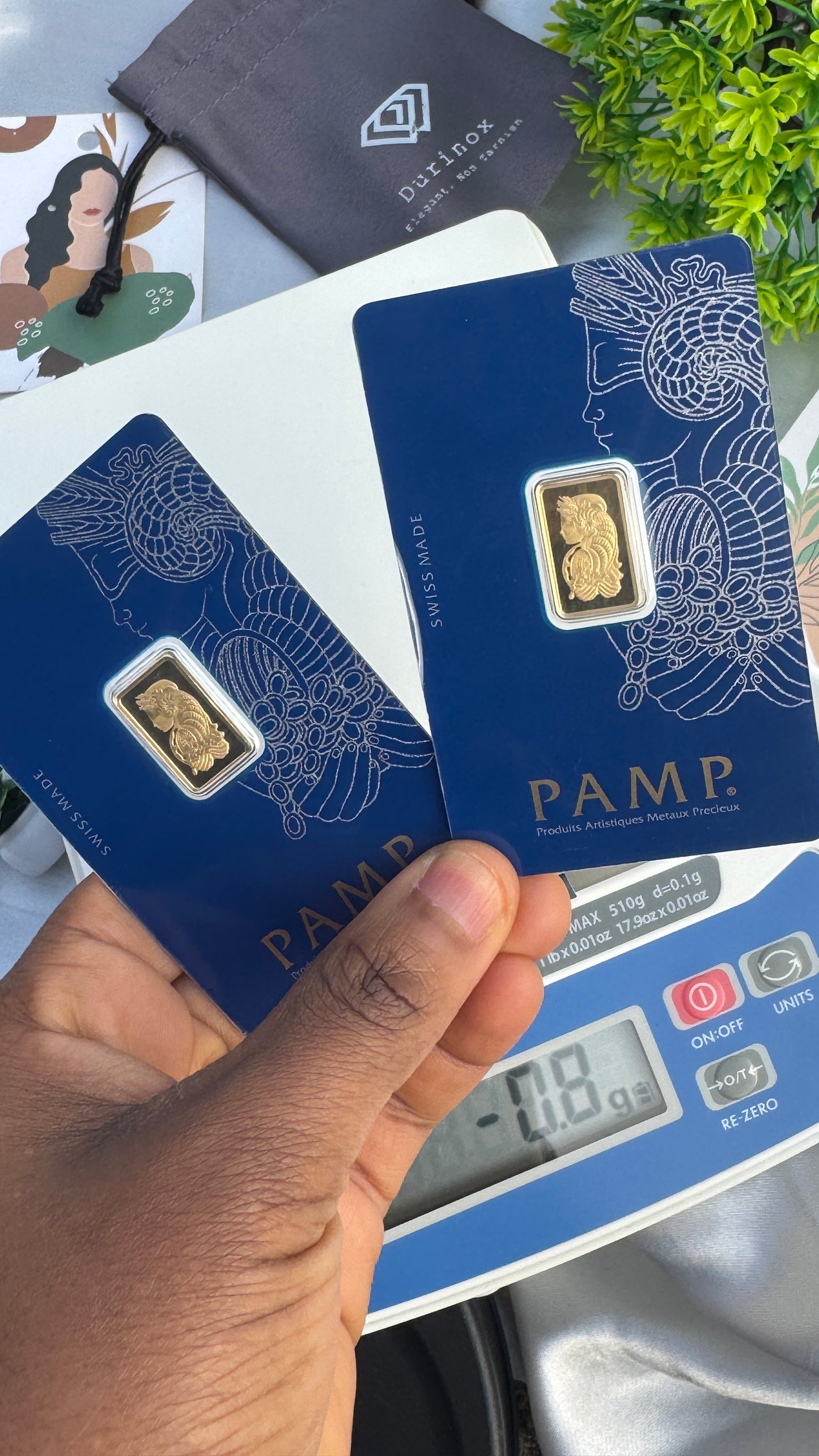 Gold bars on PAMP branded cards with a digital scale in the foreground