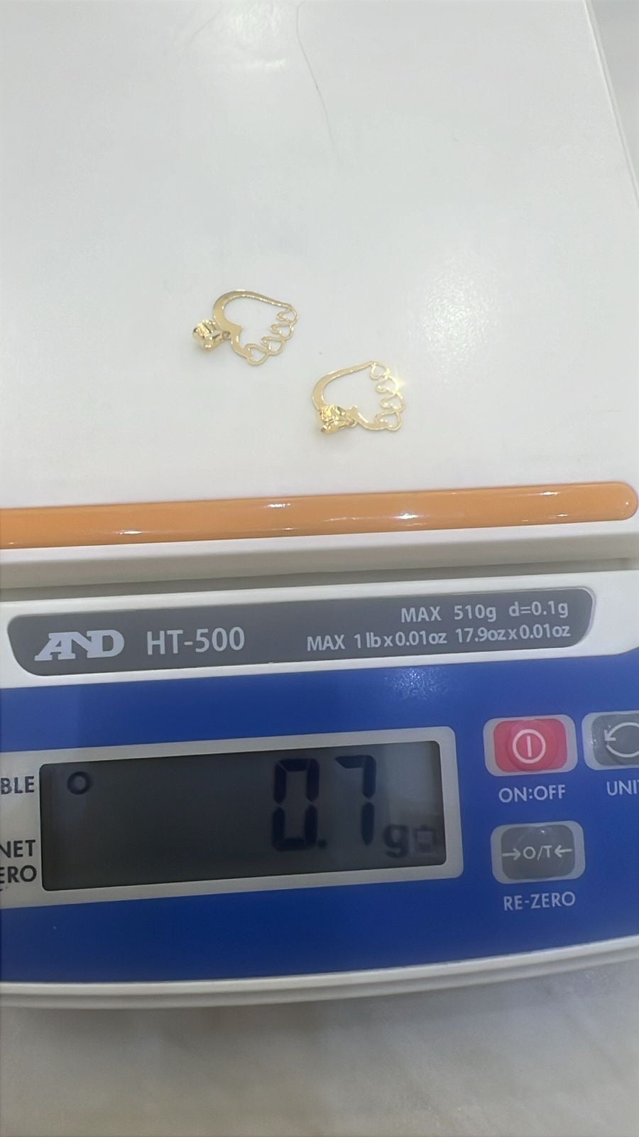 Gold pendants (Love/Heart design) on a digital scale displaying weight