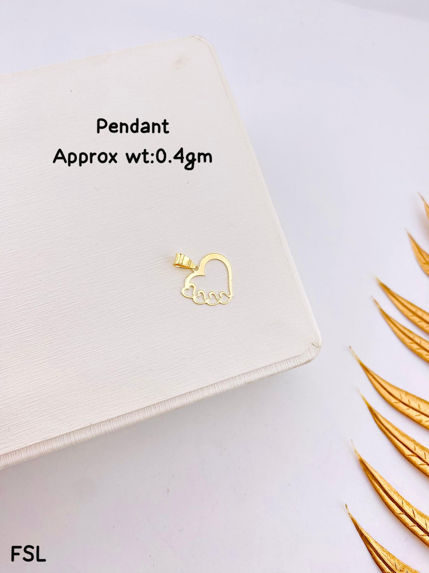 Gold pendant on a white surface with text indicating weight and brand.